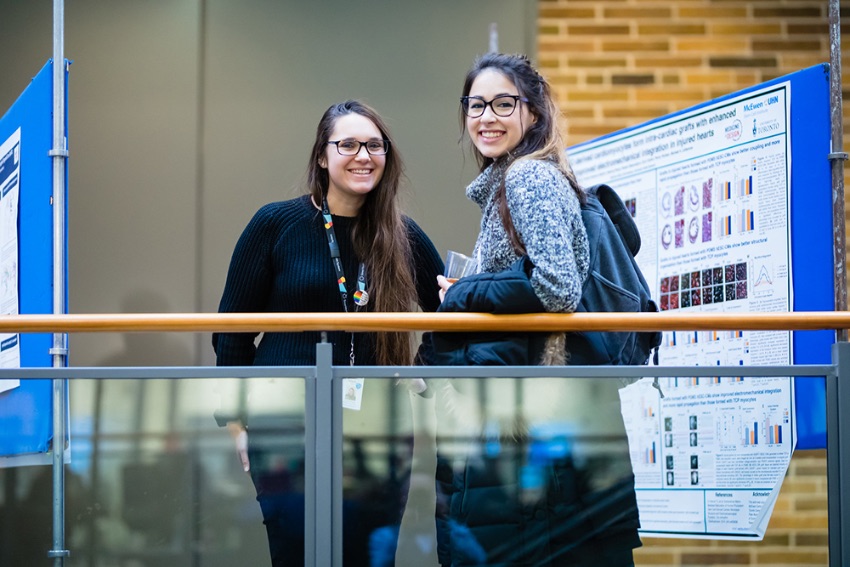 Two trainees stand by their research posters at the 2019 Medicine by Design symposium.